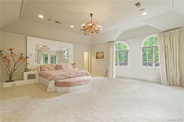 a spacious bedroom with a balcony a bed and a chandelier