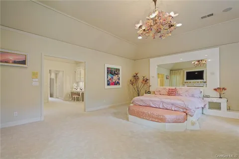 a spacious bedroom with bed and a chandelier