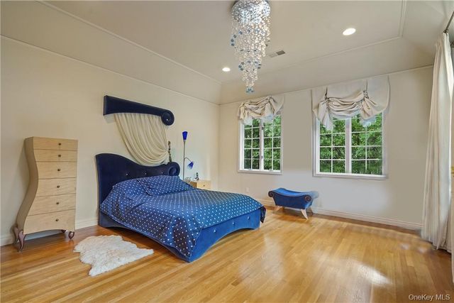a bedroom with a bed chandelier and a window
