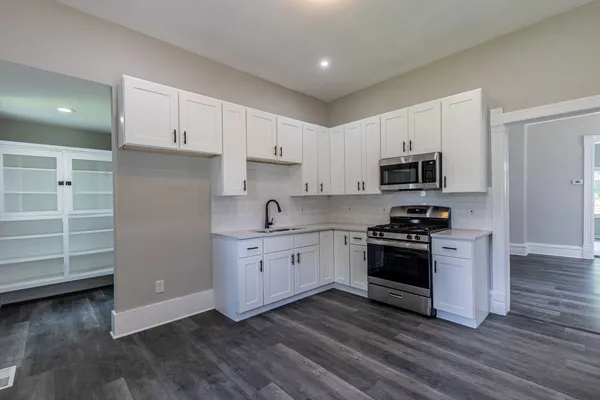 a kitchen with granite countertop white cabinets and stainless steel appliances