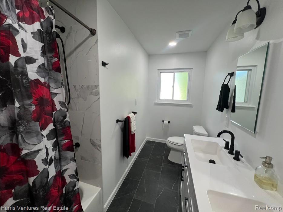 28482 Sutherland Avenue Warren, MI 48088 - Photo 20 of 25 Bathroom featuring a dual-sink vanity with white countertops, matte black fixtures, a white bathtub with marble-look tile surround, dark tile flooring, and a window