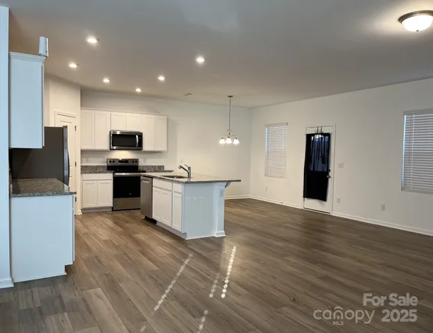 a large kitchen with kitchen island wooden floors appliances and cabinets