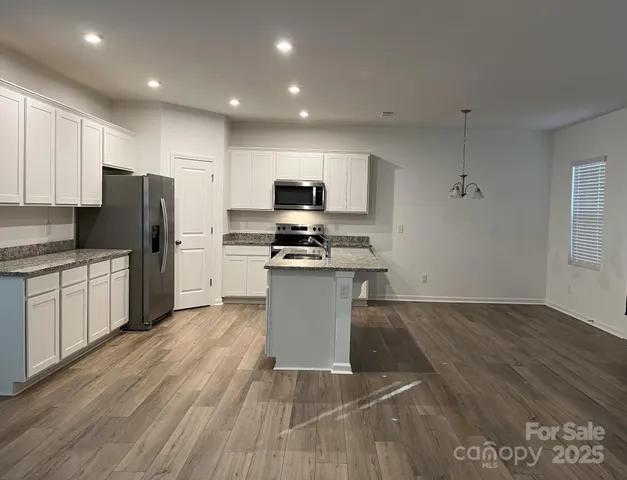 a kitchen with granite countertop a refrigerator stove top oven and sink