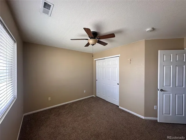 an empty room with a ceiling fan and window