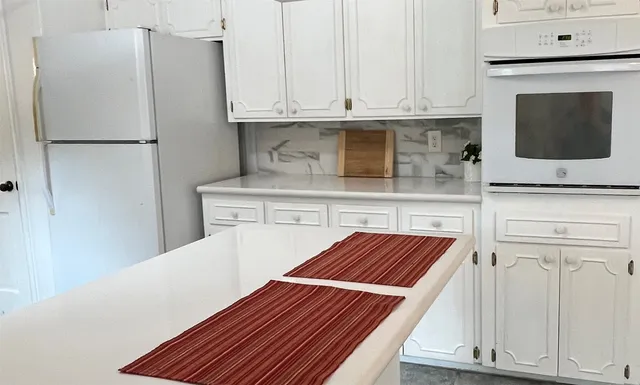 a kitchen with stainless steel appliances a refrigerator and white cabinets