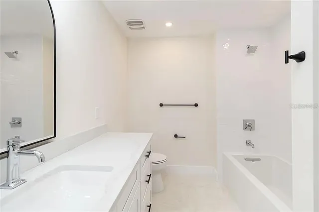 a bathroom with a granite countertop sink a toilet and shower