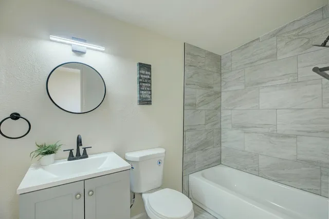 a bathroom with a toilet sink vanity tub and mirror