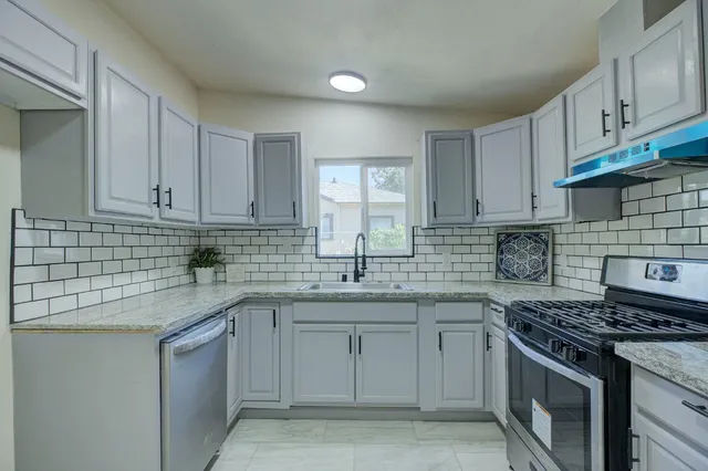 a kitchen with stainless steel appliances granite countertop a sink stove and cabinets