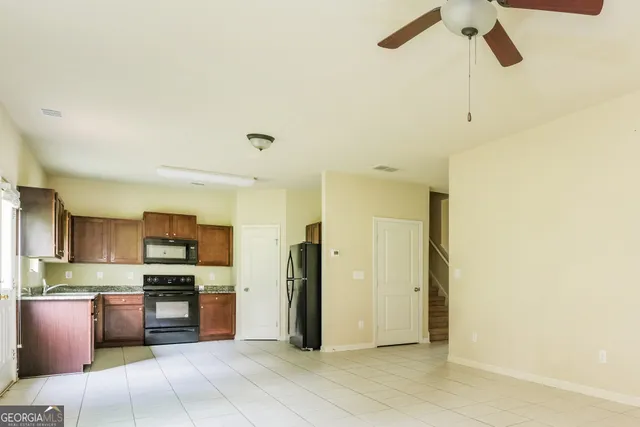 a large kitchen with stainless steel appliances kitchen island granite countertop a refrigerator and a sink