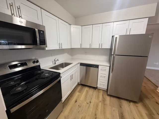a kitchen with a refrigerator stove and white cabinets