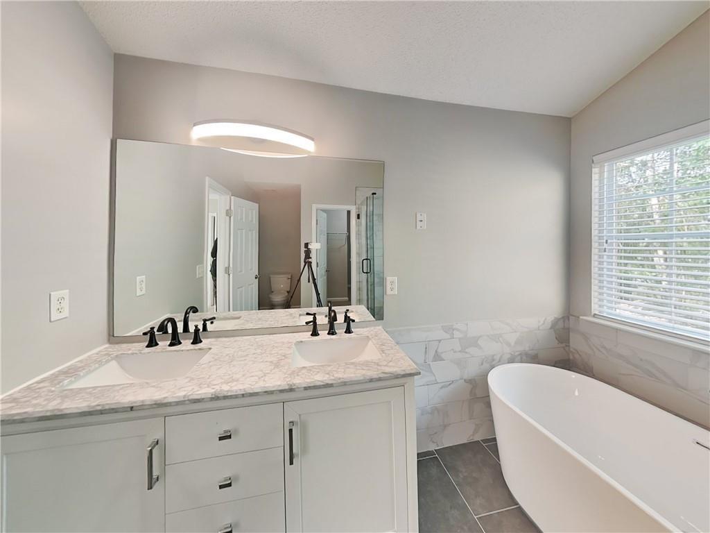 2157 Capella Circle Southwest Atlanta, GA 30331 - Photo 10 of 16 a bathroom with a granite countertop sink a large mirror a bathtub and window