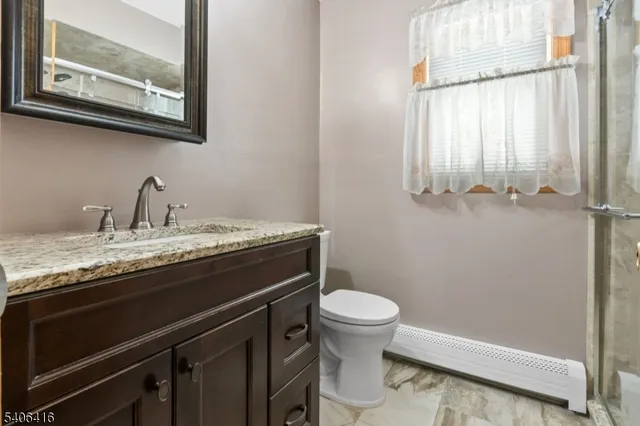 a bathroom with a granite countertop sink and a toilet