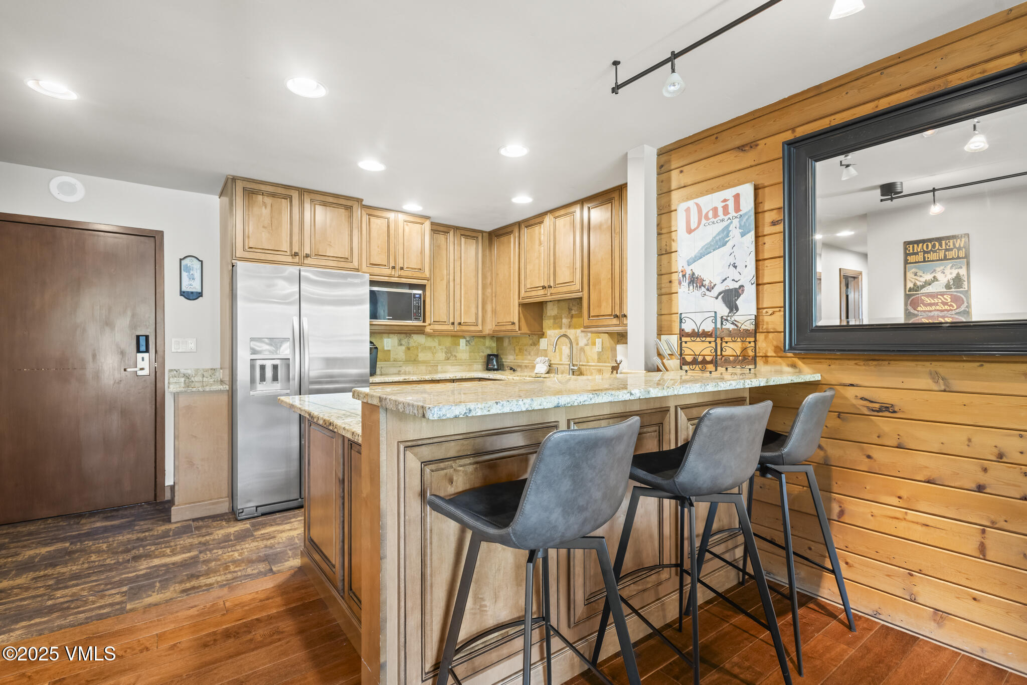 1100 North Frontage Road West, Unit 2504 Vail, CO 81657 - Photo 8 of 35 a kitchen with stainless steel appliances granite countertop a stove top oven a refrigerator a sink and a dining table with white cabinets
