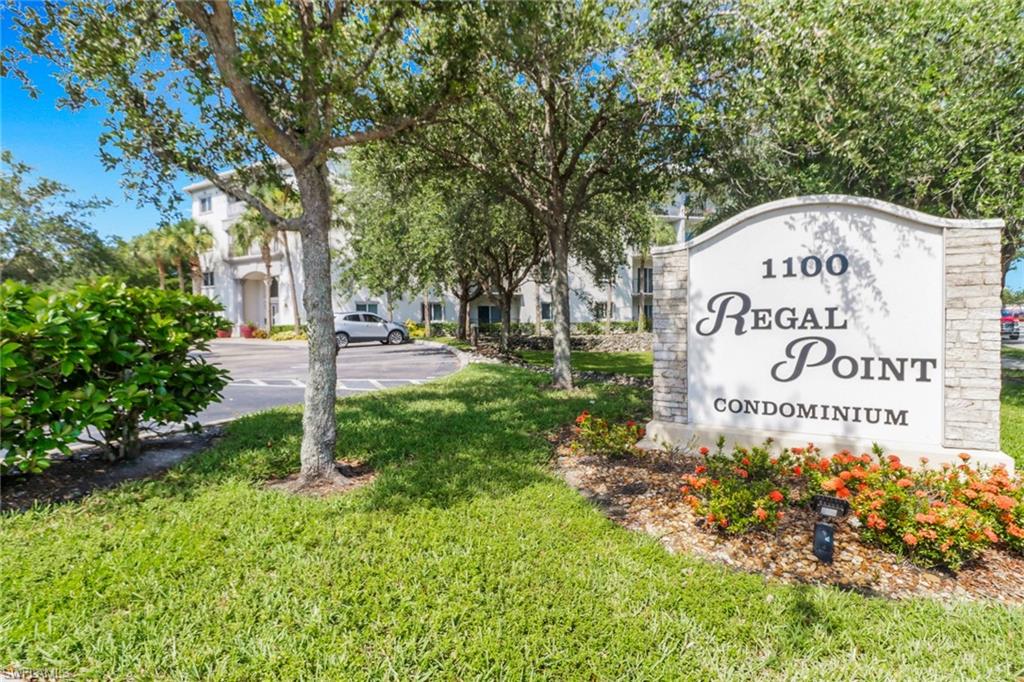 Community / neighborhood sign with a yard and a residential view