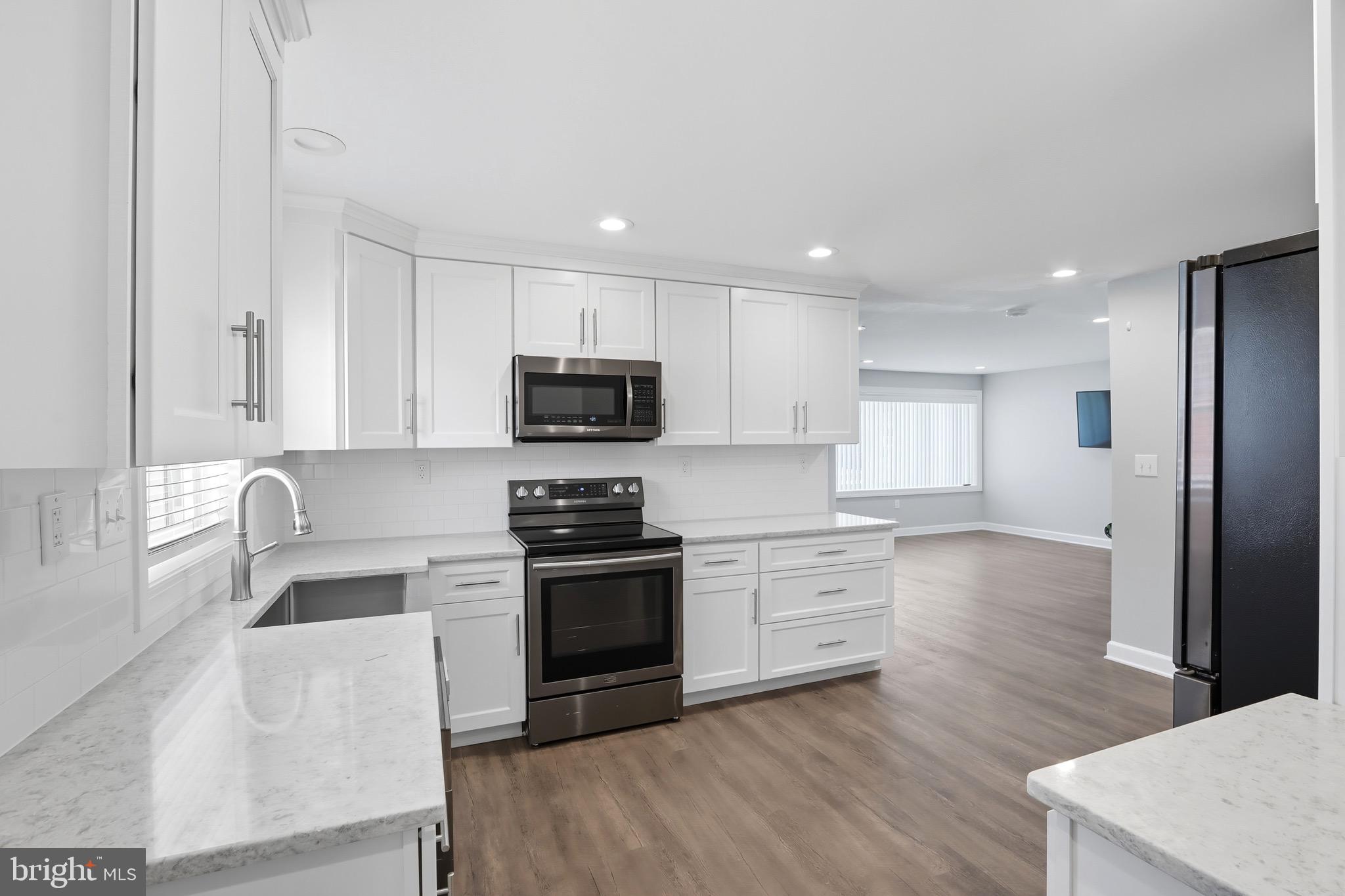 1206 Gettig Road Baltimore, MD 21237 - Photo 10 of 38 a kitchen with stainless steel appliances granite countertop a sink dishwasher a stove and a refrigerator with wooden floor
