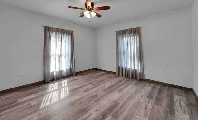 a view of an empty room with wooden floor and a window