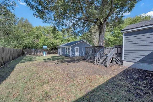 a wooden house with large trees and wooden fence
