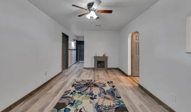 a view of a hallway with wooden floor and a ceiling fan