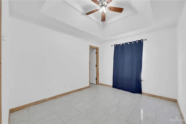 an empty room with a chandelier fan and windows