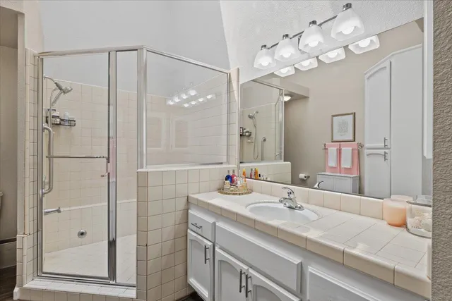 a bathroom with a sink vanity granite shower and a mirror