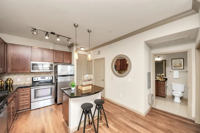 a kitchen with stainless steel appliances granite countertop a refrigerator a oven a sink a stove and white cabinets with wooden floor