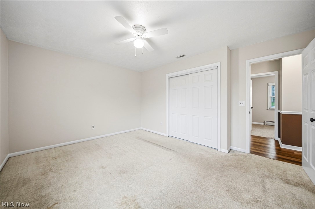 10397 Prouty Road Painesville, OH 44077 - Photo 11 of 32 Unfurnished bedroom with carpet, a closet, a ceiling fan, and baseboard heating