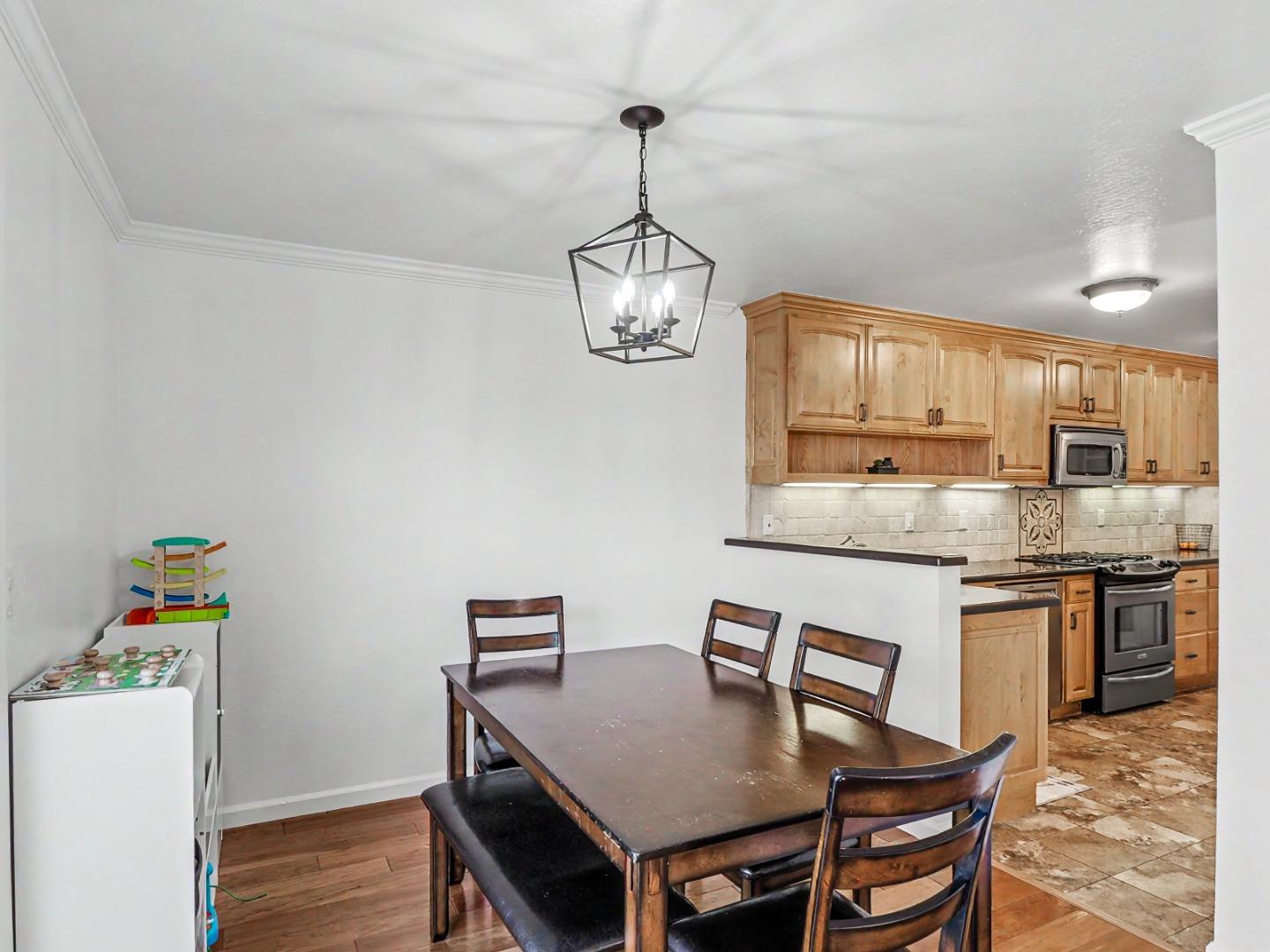 1310 Primavera Street, Unit 109 Salinas, CA 93901 - Photo 8 of 37 a kitchen with stainless steel appliances granite countertop a stove top oven a sink a dining table and chairs with wooden floor