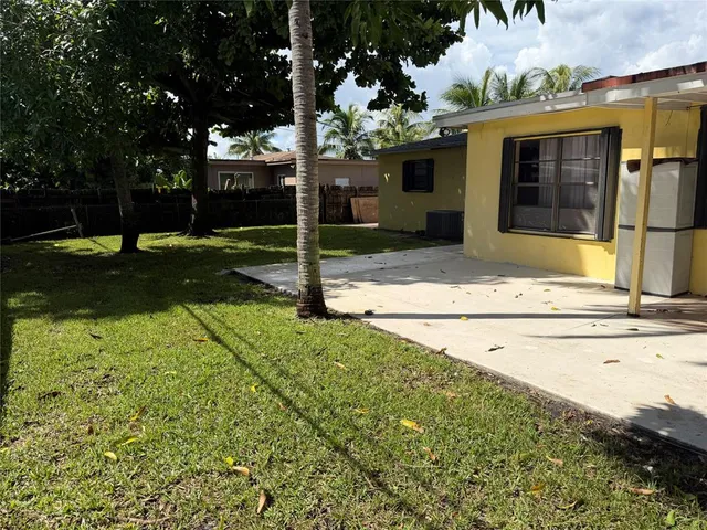 a view of backyard with tree and wooden fence