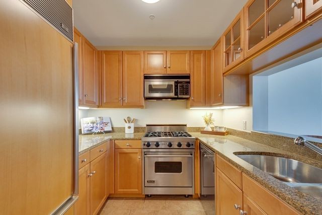 a kitchen with stainless steel appliances granite countertop a sink a stove and a microwave oven with cabinets