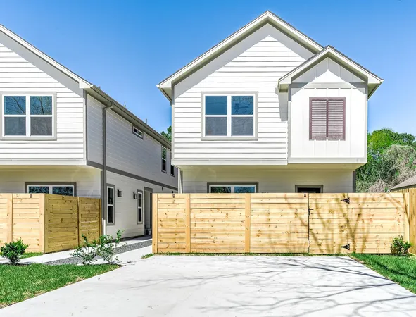 a view of a house with a small yard and wooden fence
