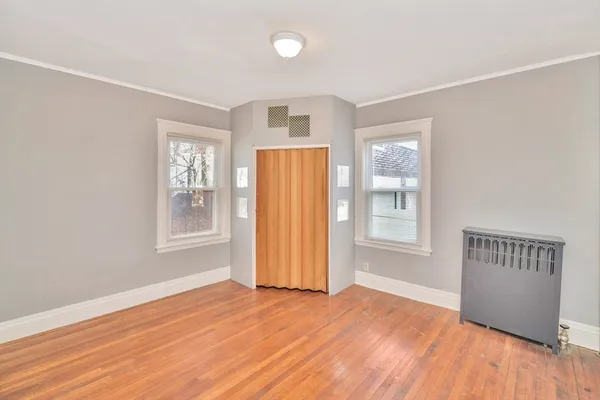 an empty room with wooden floor and windows