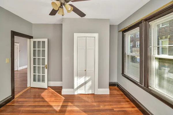 a view of empty room with wooden floor and fan