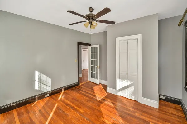 a view of an empty room with wooden floor and a window