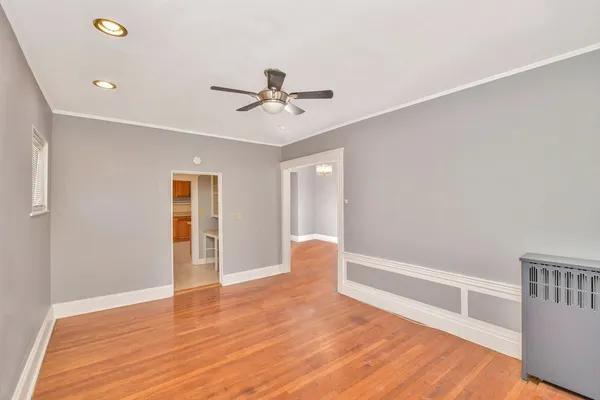 a view of an empty room with a window and wooden floor