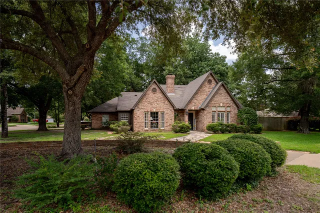 a front view of a house with a yard and large trees