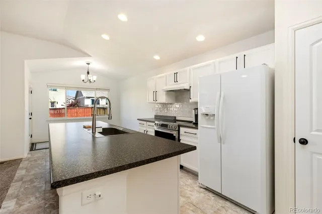 a kitchen with stainless steel appliances granite countertop a refrigerator a stove and a sink