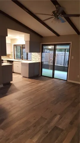 a view of an empty room with window and wooden floor