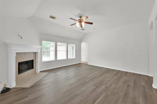 a view of empty room with wooden floor fireplace and a window