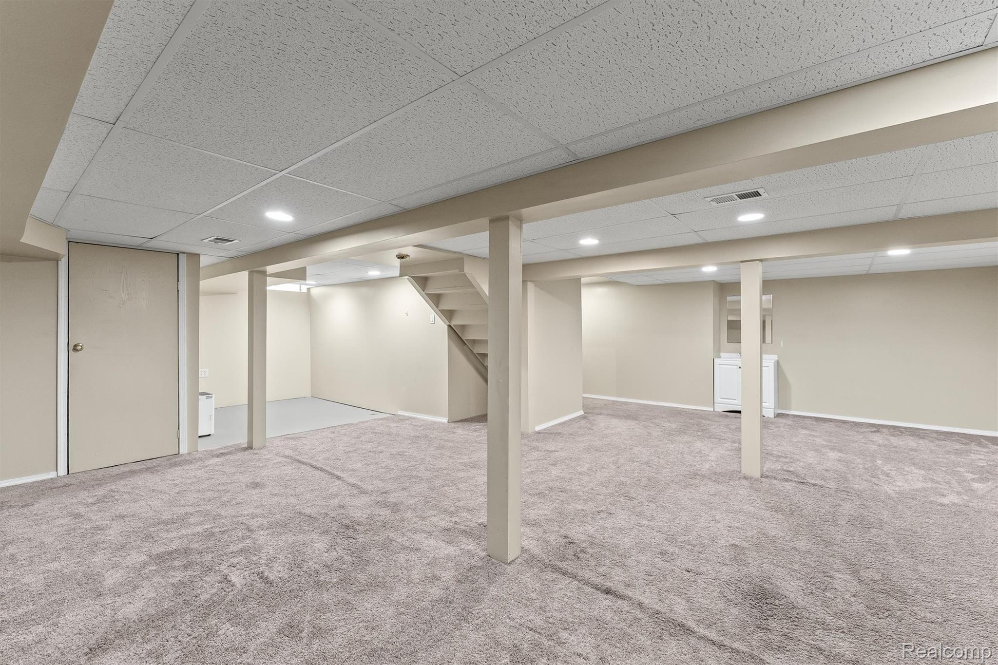 2118 Rutgers Drive Troy, MI 48085 - Photo 29 of 39 Spacious lower level featuring plush grey carpeting, recessed lighting, drop ceiling, painted support beams, and an exposed staircase