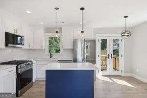 a kitchen with stainless steel appliances granite countertop a sink a stove a refrigerator and a wooden floor