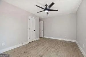 an empty room with wooden floor and ceiling fan