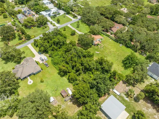 an aerial view of residential houses with outdoor space and trees