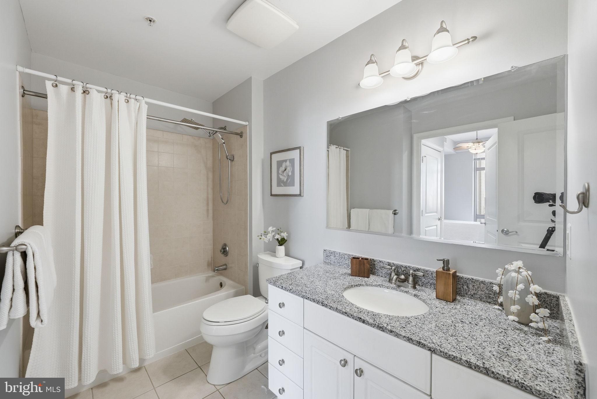 3650 South Glebe Road, Unit 1145 Arlington, VA 22202 - Photo 12 of 42 a bathroom with a granite countertop sink toilet a mirror a vanity and shower