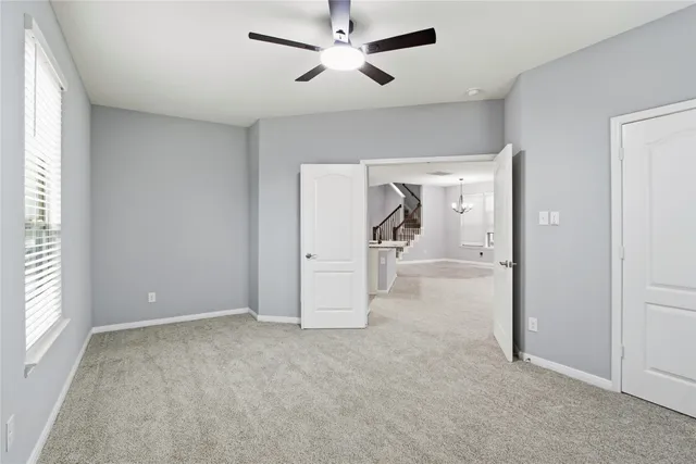 an empty room with chandelier fan and windows