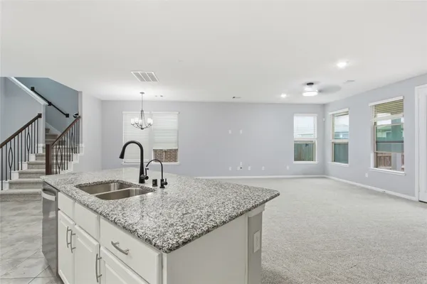 a kitchen with granite countertop a sink and white cabinets