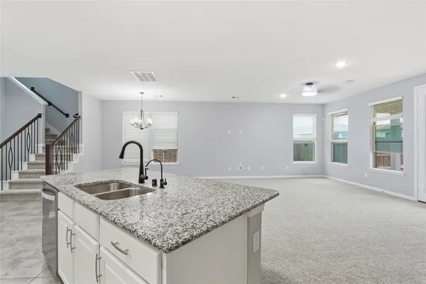 a kitchen with granite countertop a sink and white cabinets