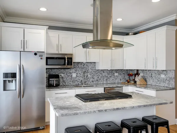a kitchen with stainless steel appliances granite countertop a sink a stove a refrigerator and island