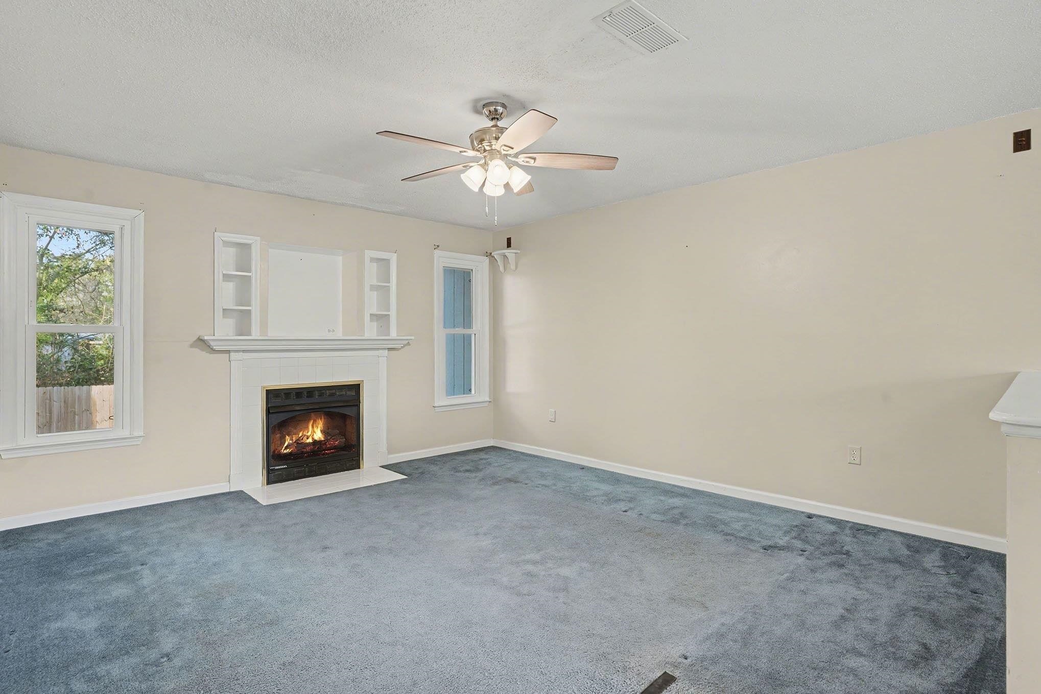 152 Brookgate Drive Myrtle Beach, SC 29579 - Photo 4 of 35 Unfurnished living room with a fireplace with flush hearth, carpet floors, a textured ceiling, and a ceiling fan