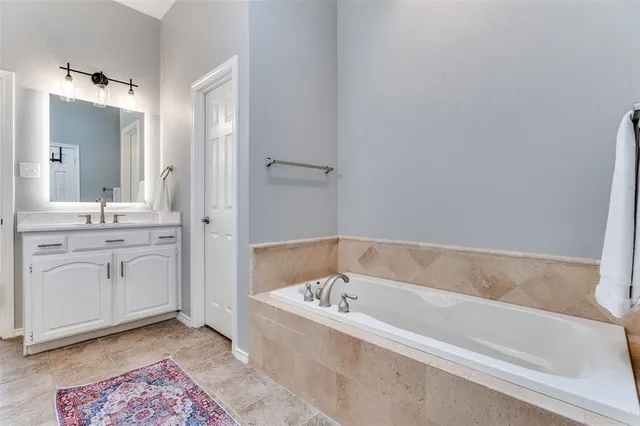 a bathroom with a tub sink and mirror