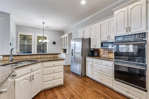a kitchen with granite countertop white cabinets and stainless steel appliances
